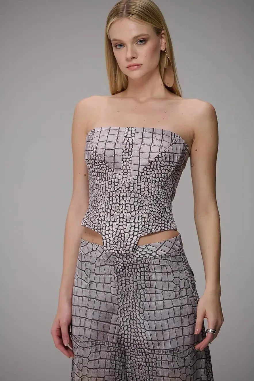 A model wearing a strapless tube top and matching high-waisted pants set in a gray and white crocodile-embossed pattern, set against a plain gray studio background.