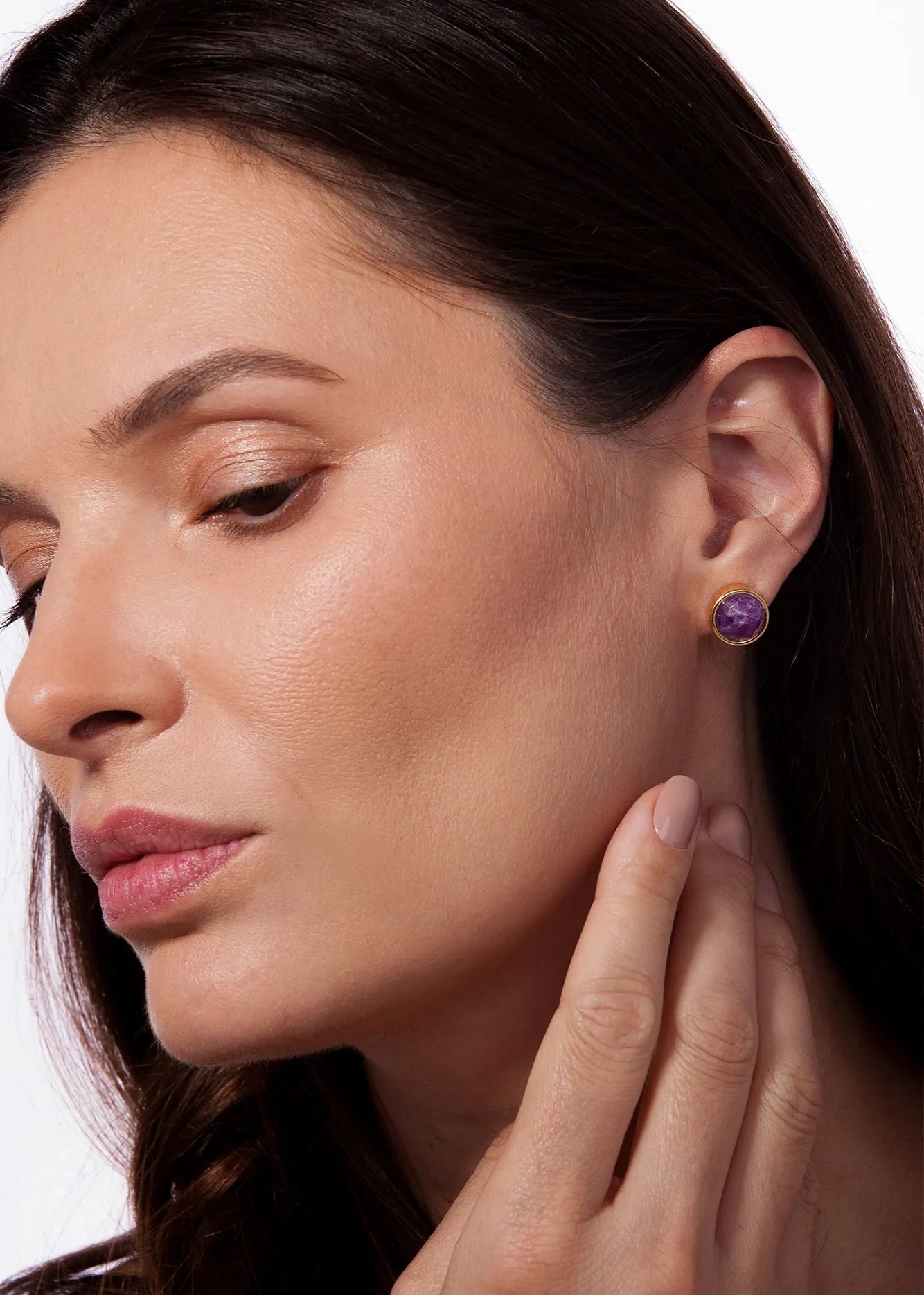 Close-up of a woman wearing a purple earring on a white background