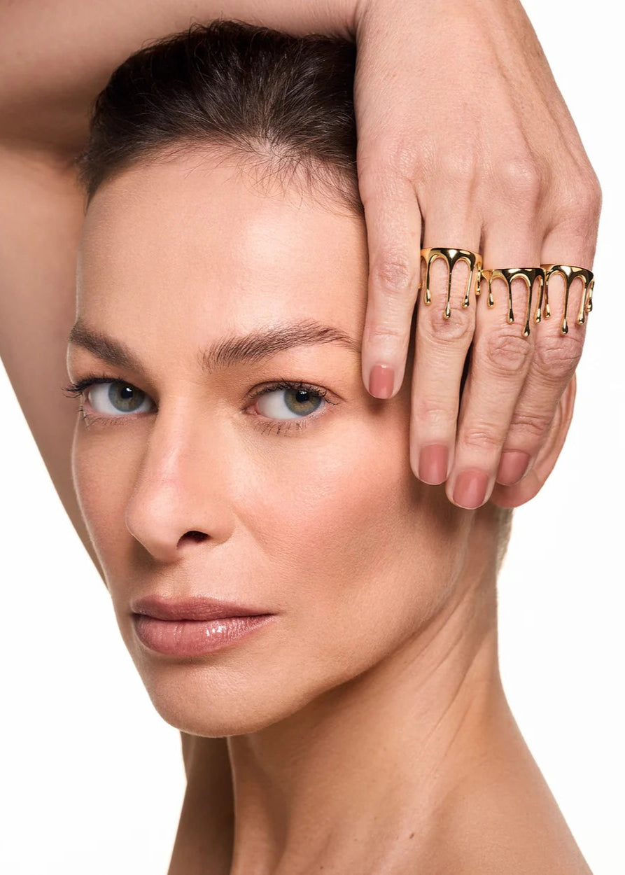 Woman with gold rings on fingers against a white background