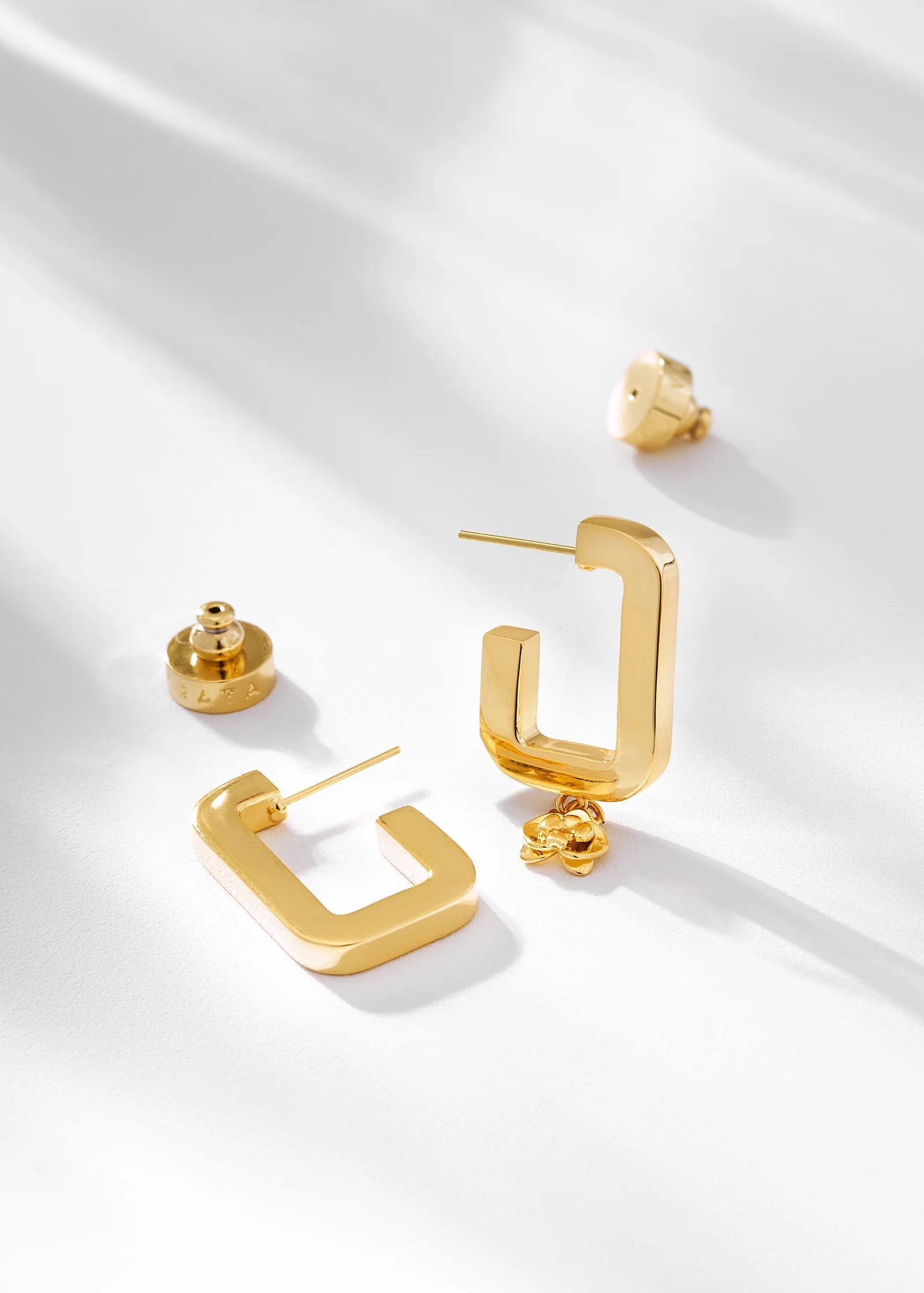 Gold hoop earrings on a white fabric background