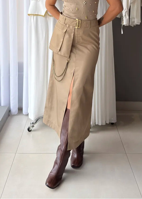 Woman in beige sleeveless top and skirt with brown boots standing in a clothing store.