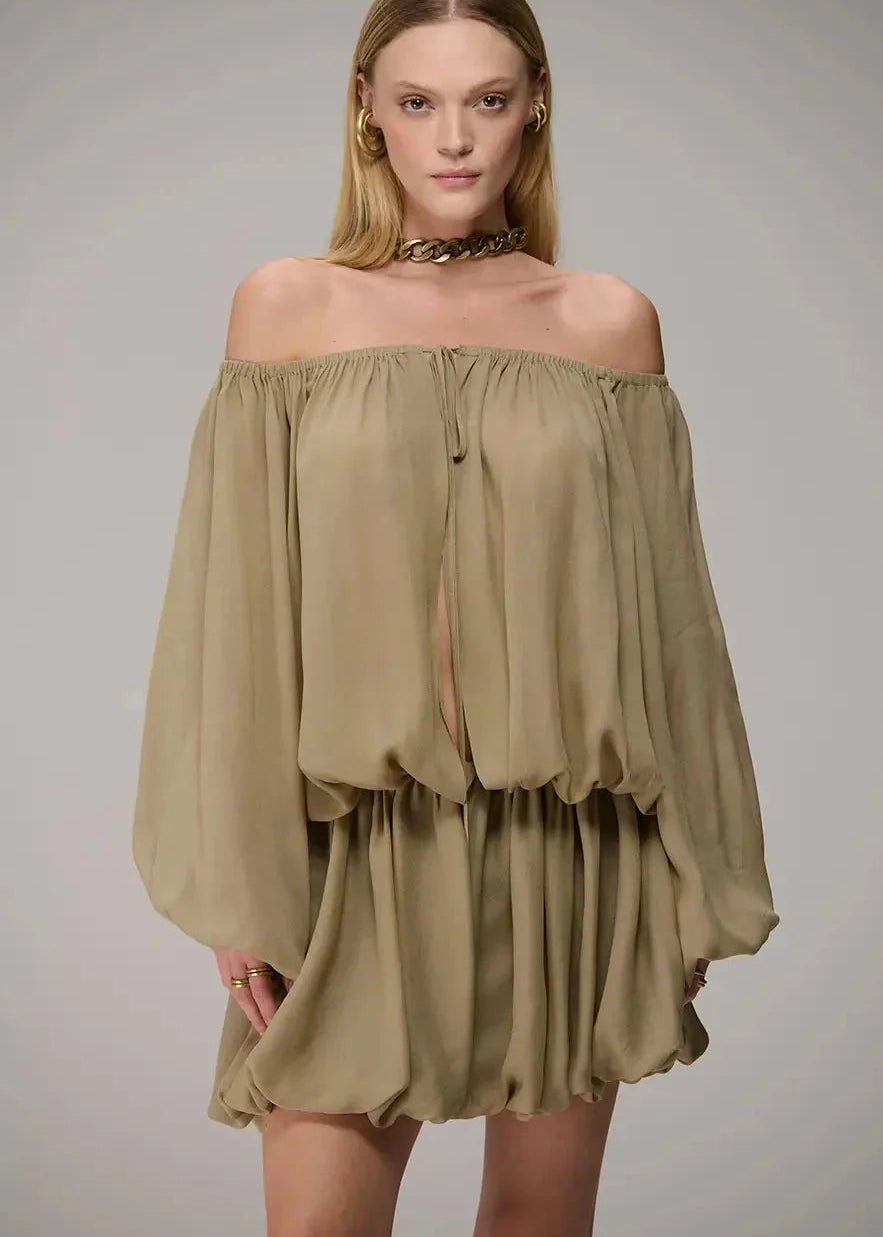 Woman wearing an off-shoulder beige dress against a gray background