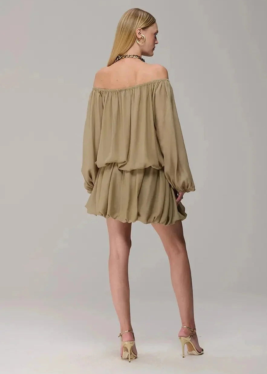 Woman wearing a green off-shoulder dress on a plain background