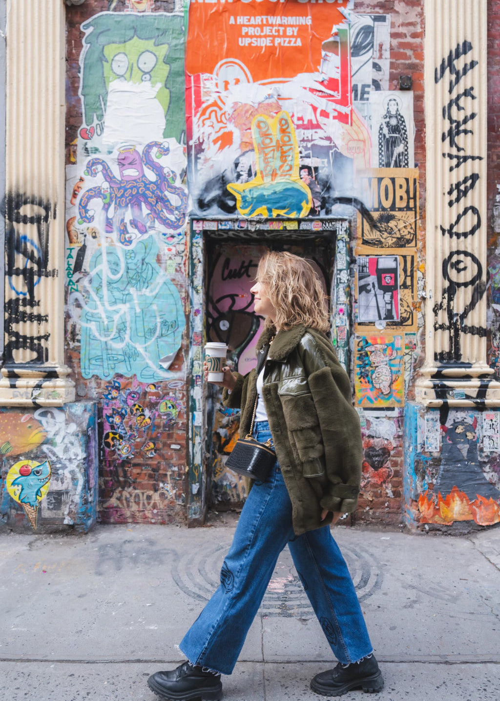 Person walking past a wall covered in graffiti and street art