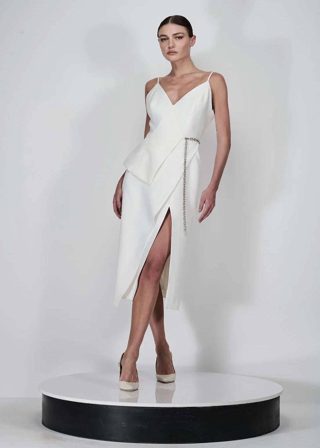 Woman wearing a white dress with a slit on a white background