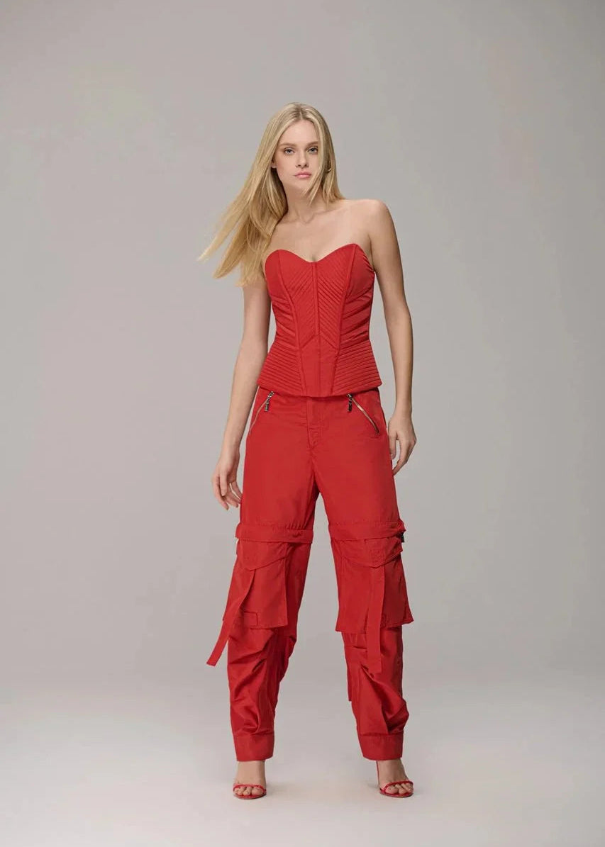 Woman wearing a red strapless top and cargo pants on a gray background