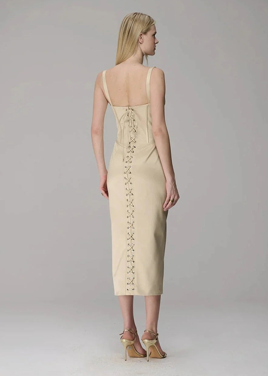 Woman wearing a beige dress with lace-up back on a plain background