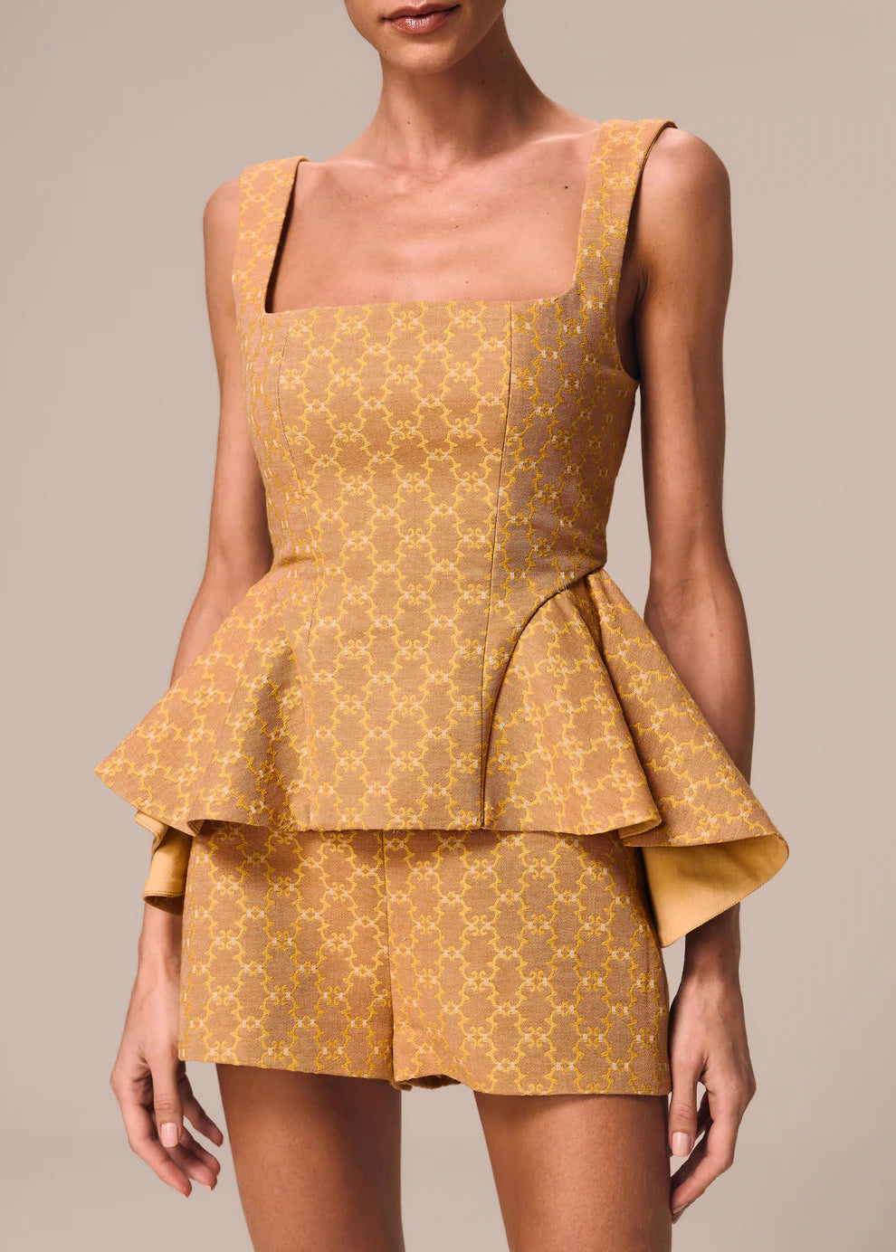 Yellow patterned peplum dress on a neutral background