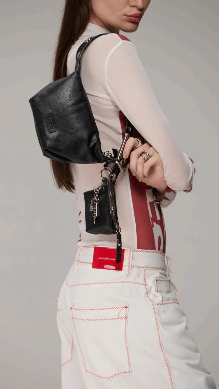 Person wearing a black backpack with a keychain on a plain background