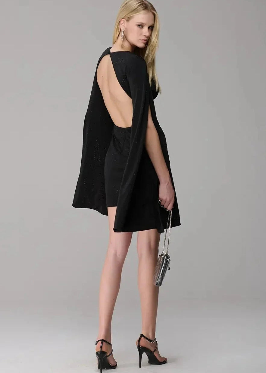 Woman wearing a black dress with cut-out back on a gray background