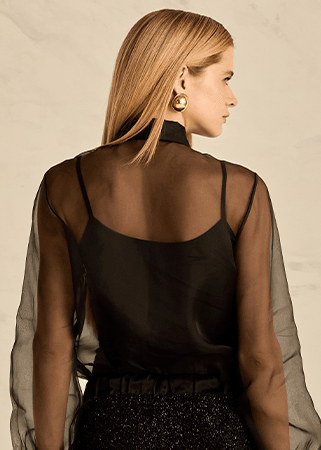Woman wearing a black tank top with a sheer blouse 