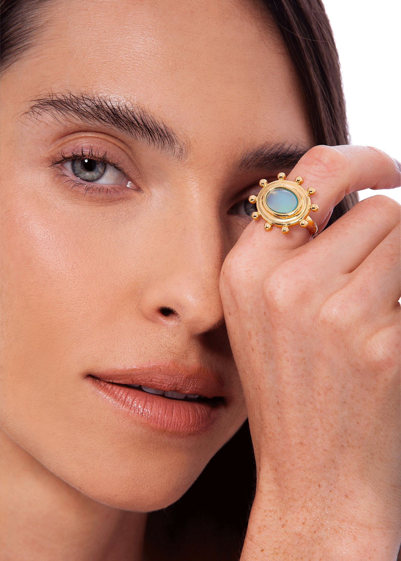 Woman wearing a gold ring with a green gemstone on her finger