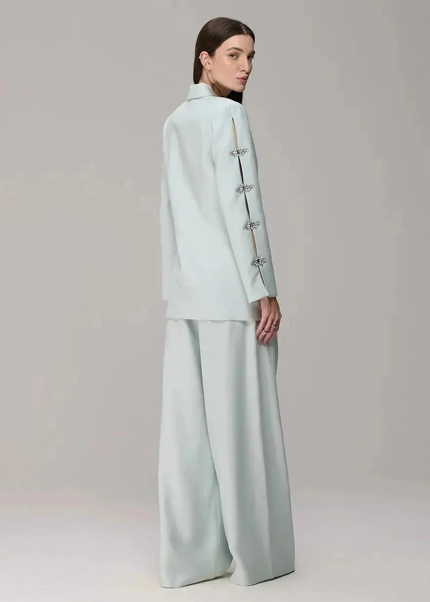 Woman wearing a light blue outfit with wide-leg pants on a plain background