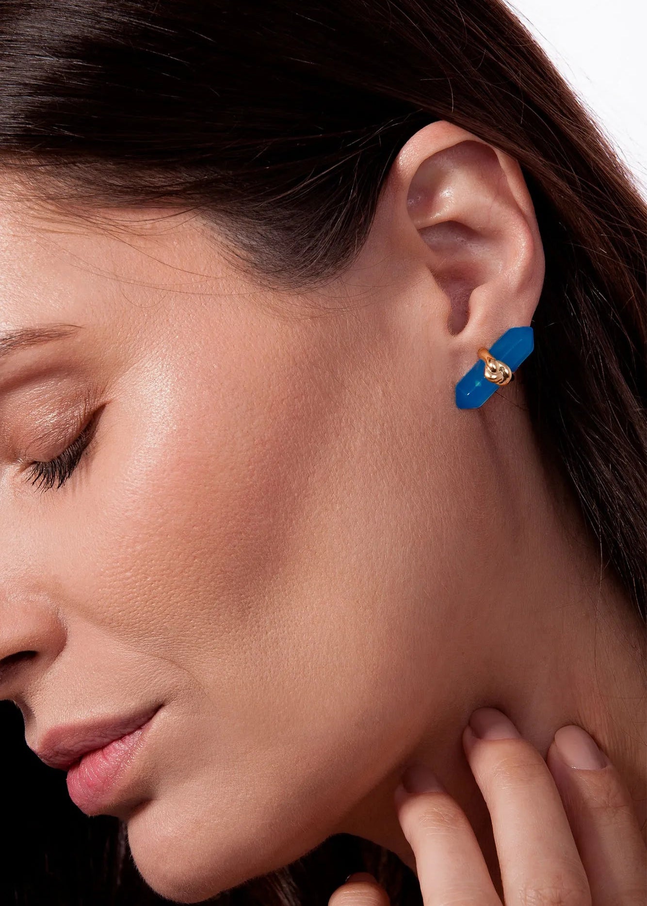 Close-up of a woman wearing a blue earring with gold accents.