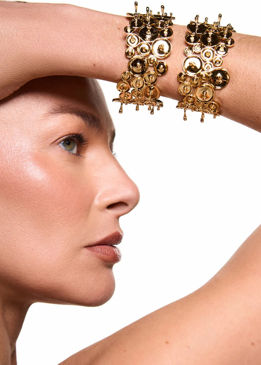 Woman wearing gold bracelets with a neutral background