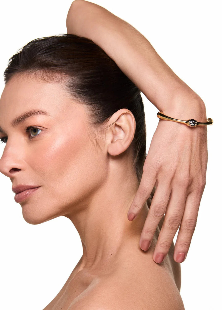 Woman with a gold bracelet on her wrist against a white background