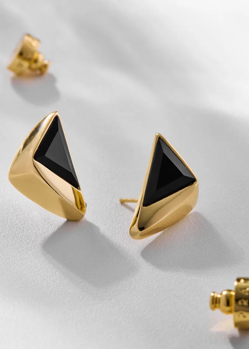Gold triangle-shaped earrings with black centers on a light gray background