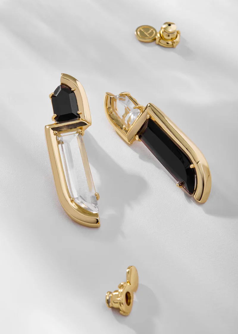 Gold and black earrings on a light gray background