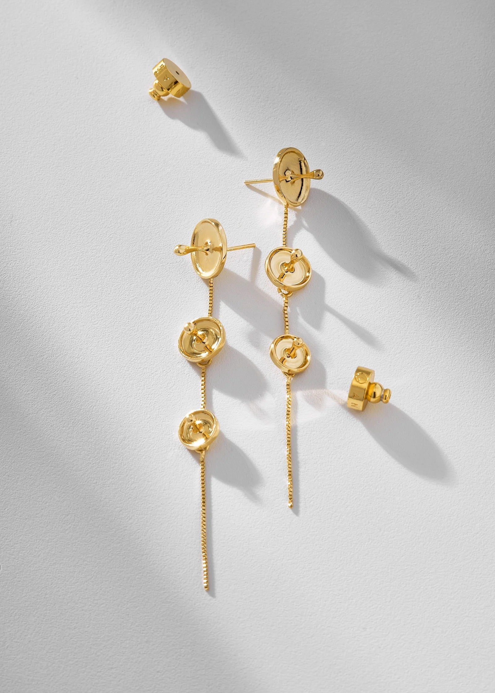 Gold earrings on a light gray background