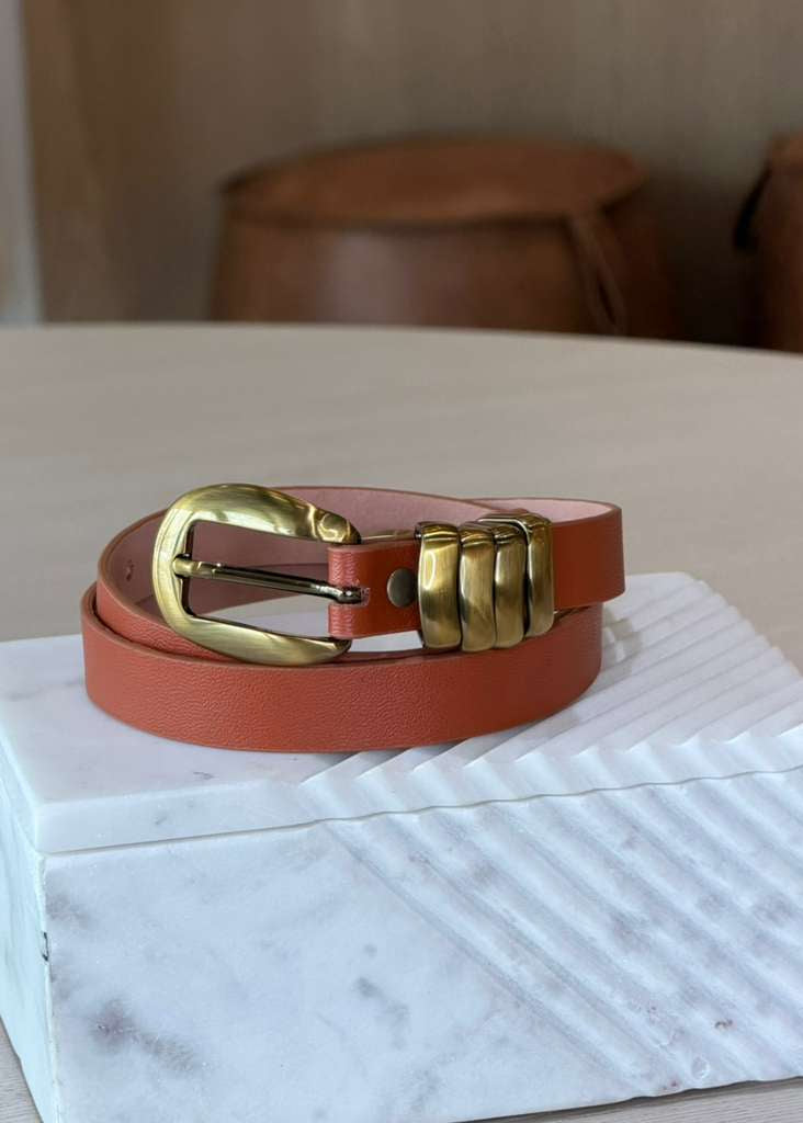 Brown leather belt with gold buckle on a marble surface