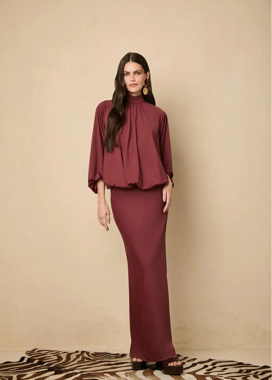 Woman wearing a burgundy dress against a beige background