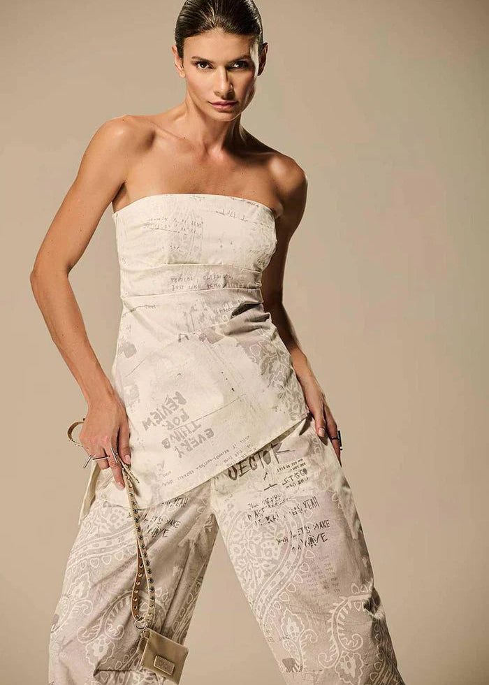 Woman wearing a strapless, textured white dress against a beige background