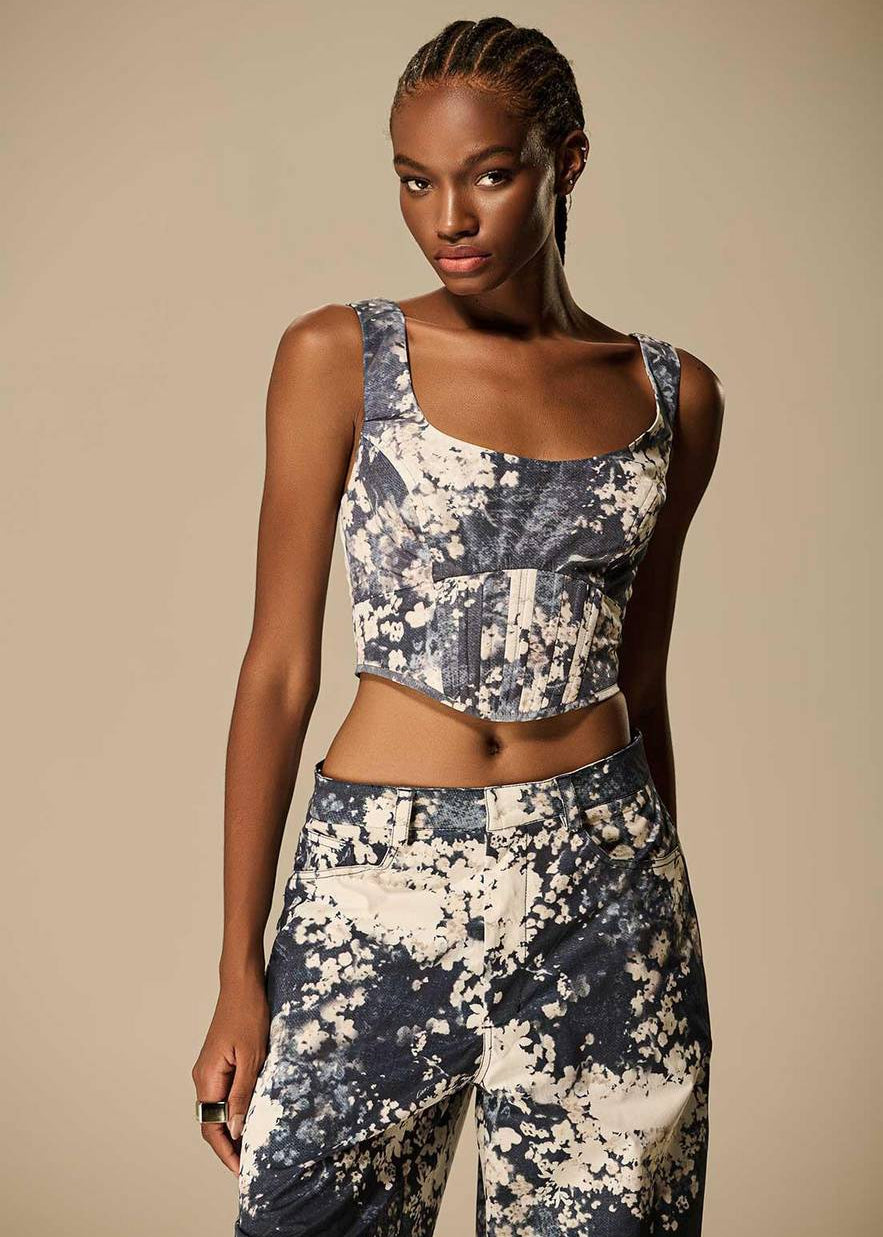 Woman wearing a floral sports bra and leggings set against a beige background