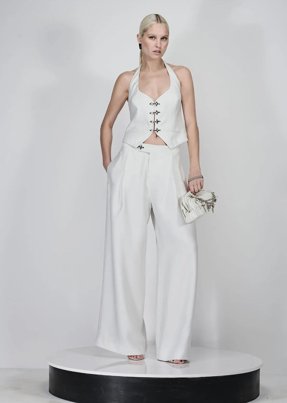 Woman in a white outfit with wide-leg pants and a halter top on a white background