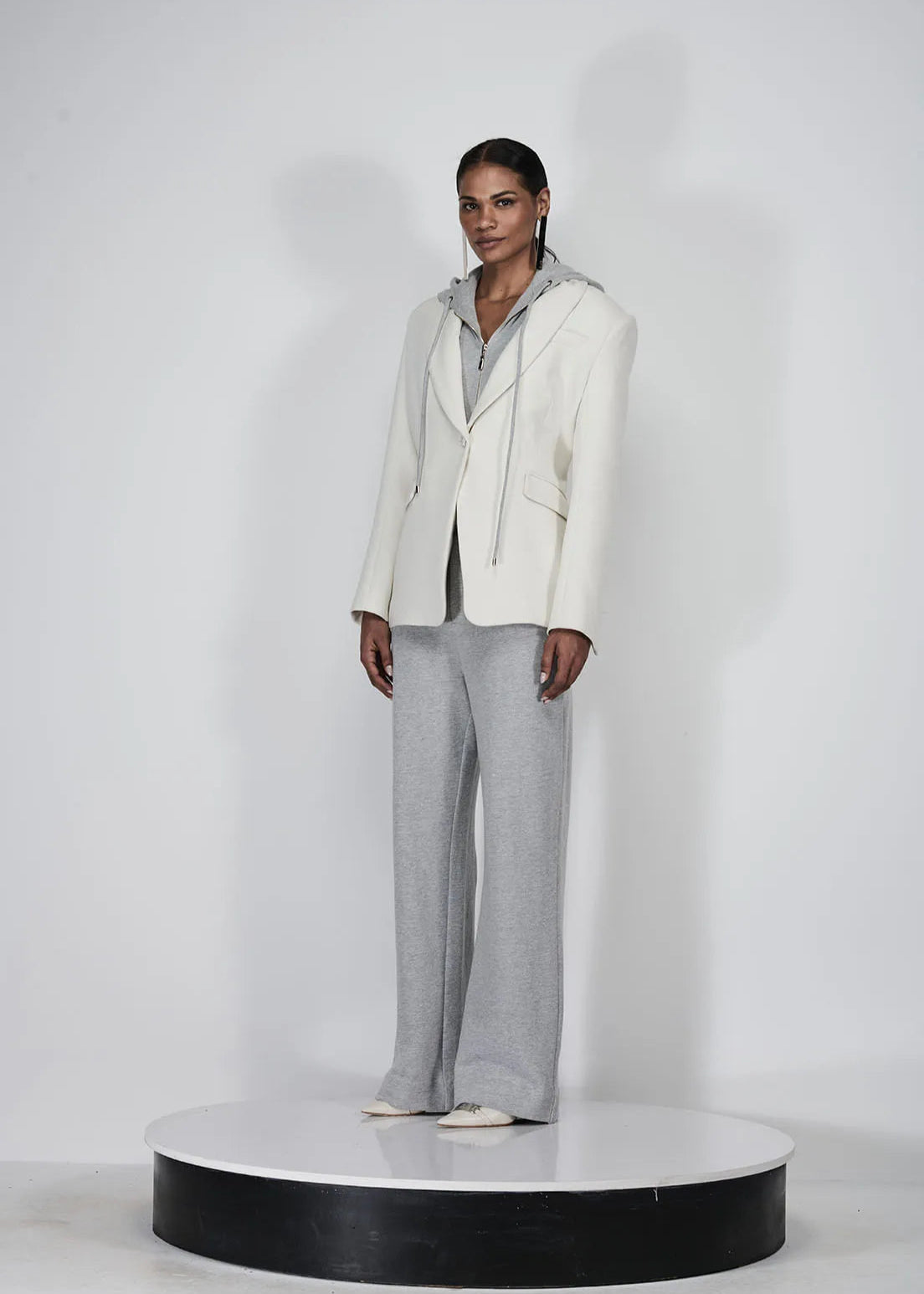 Person wearing a white blazer and gray pants on a white background