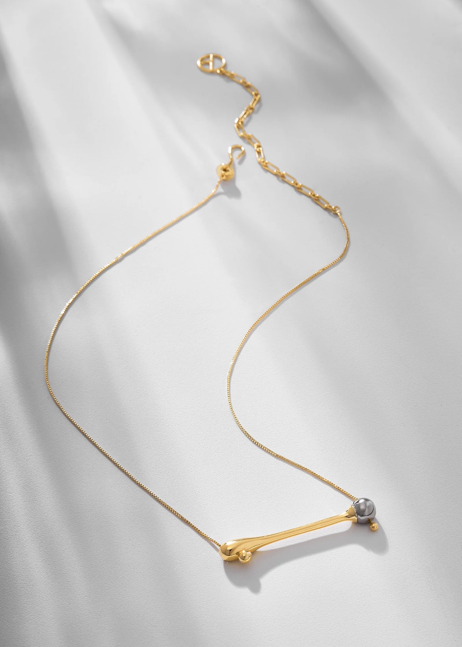 Gold necklace with a small pendant on a light gray background