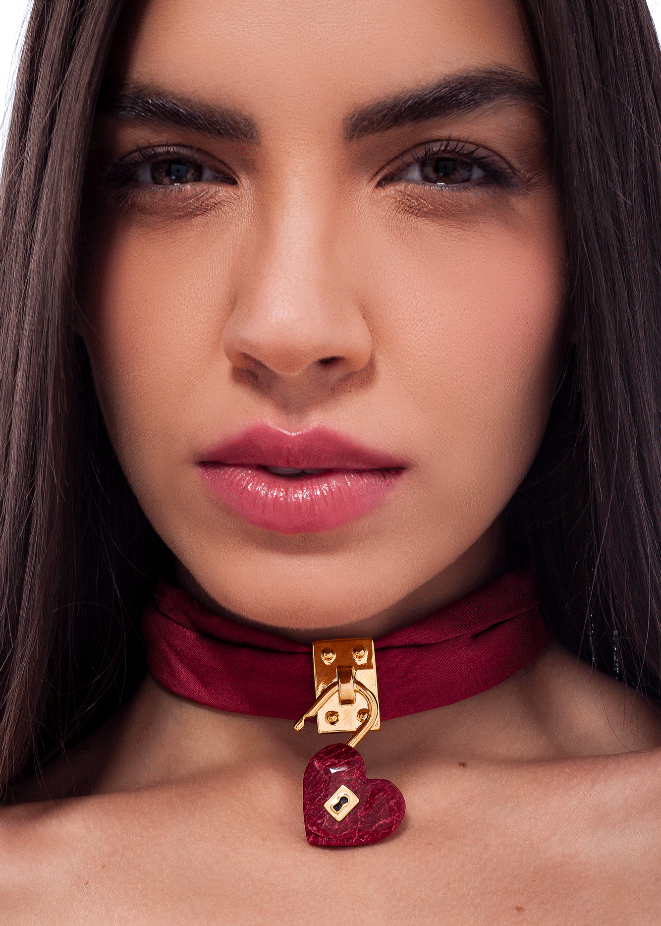 Close-up of a woman wearing a red choker with a heart pendant.