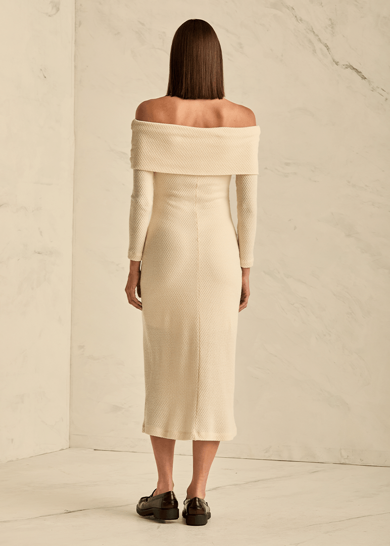 Woman wearing a beige off-shoulder dress against a neutral background