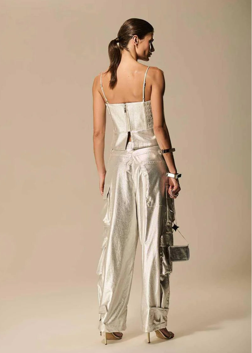 Woman wearing a silver strapless top and wide-leg pants against a beige background