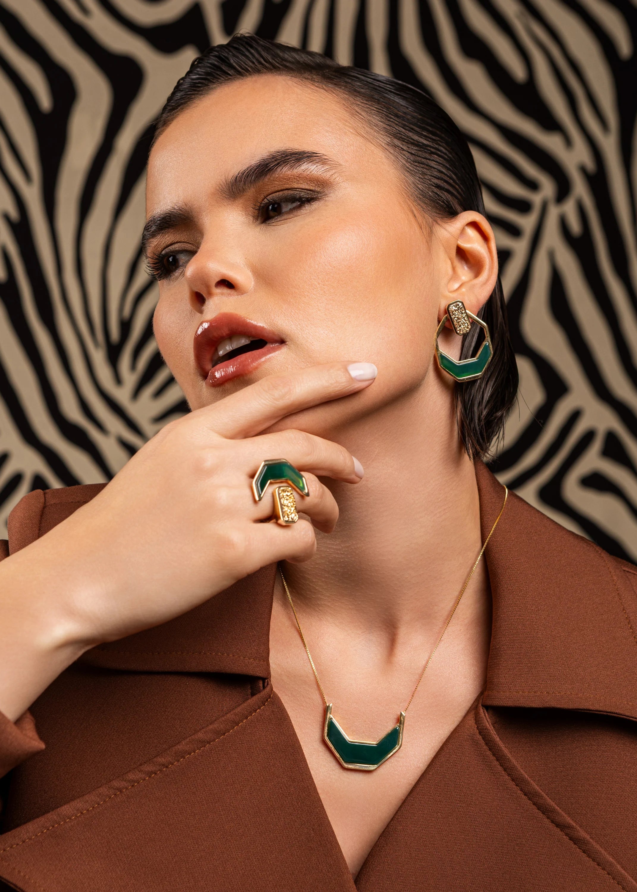 Woman wearing green and gold jewelry against a zebra-patterned background