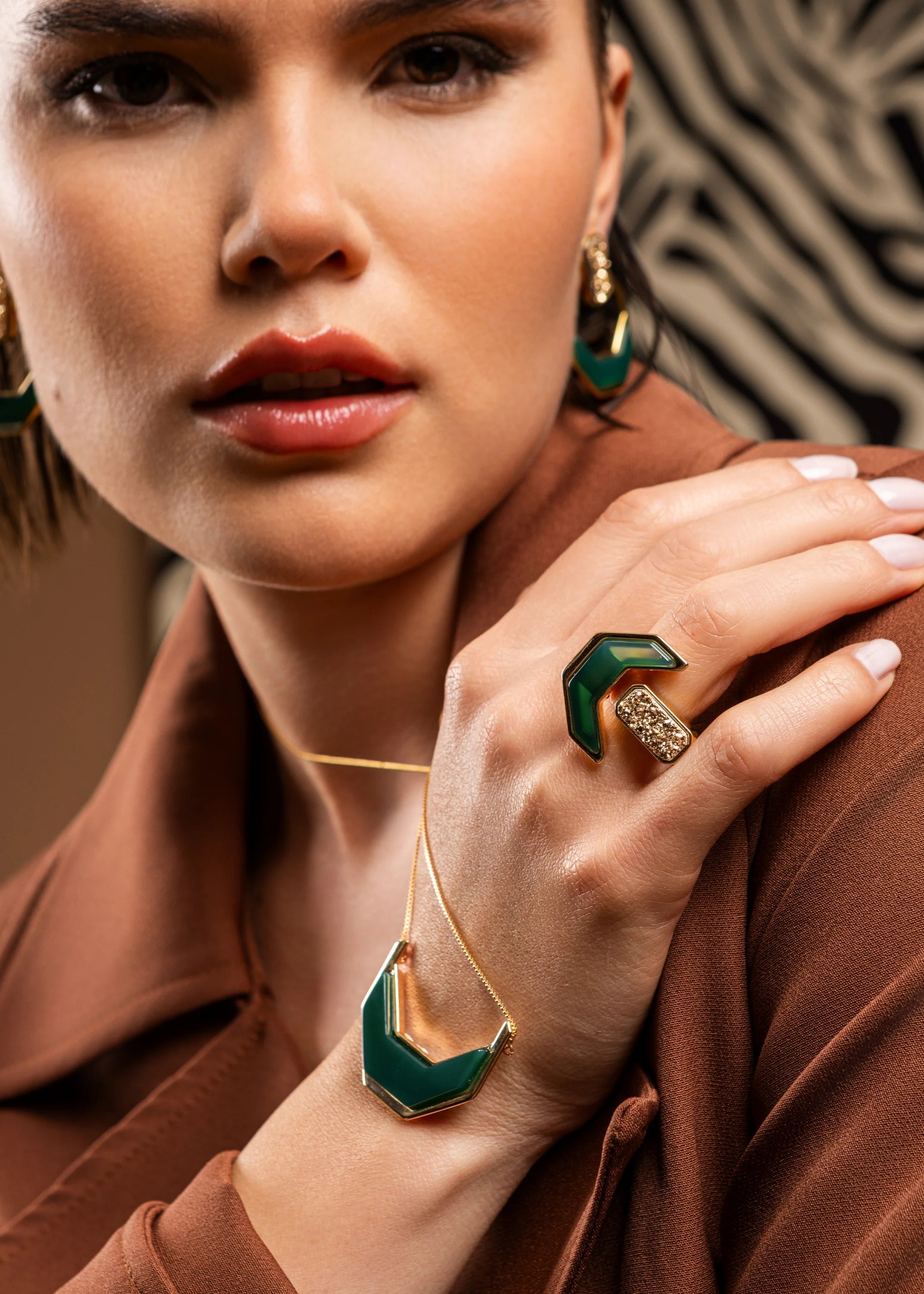 Woman wearing green and gold jewelry against a patterned background