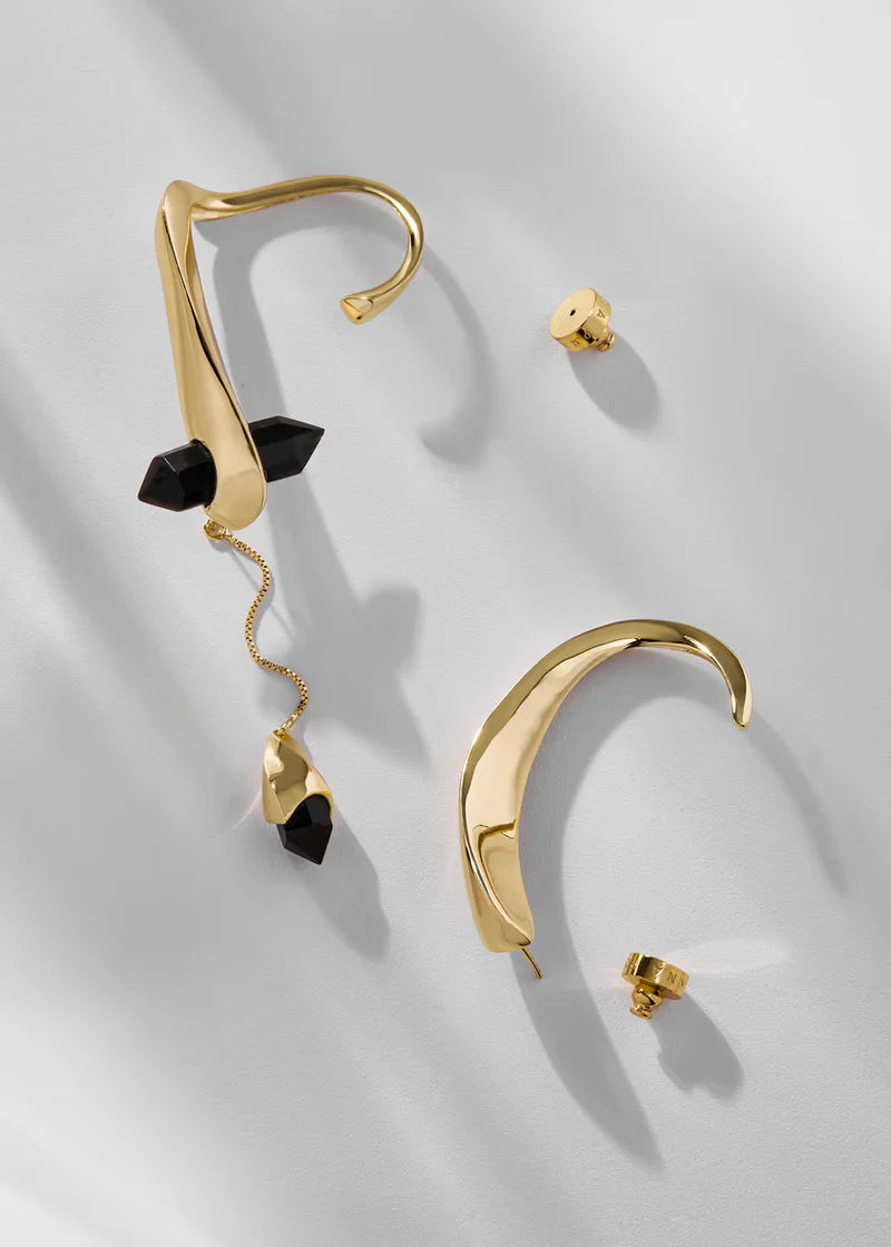 Gold earrings with black accents on a light gray background