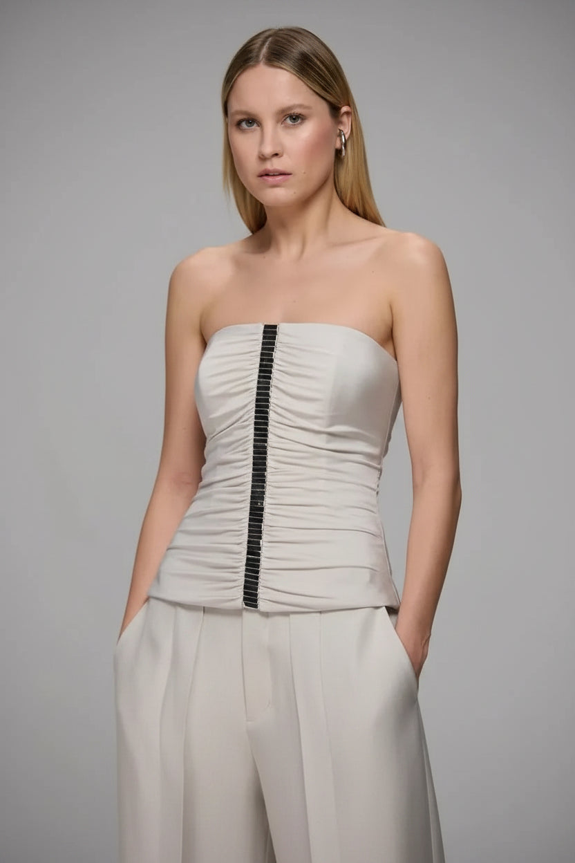 Woman wearing a strapless top and pants with a gray background