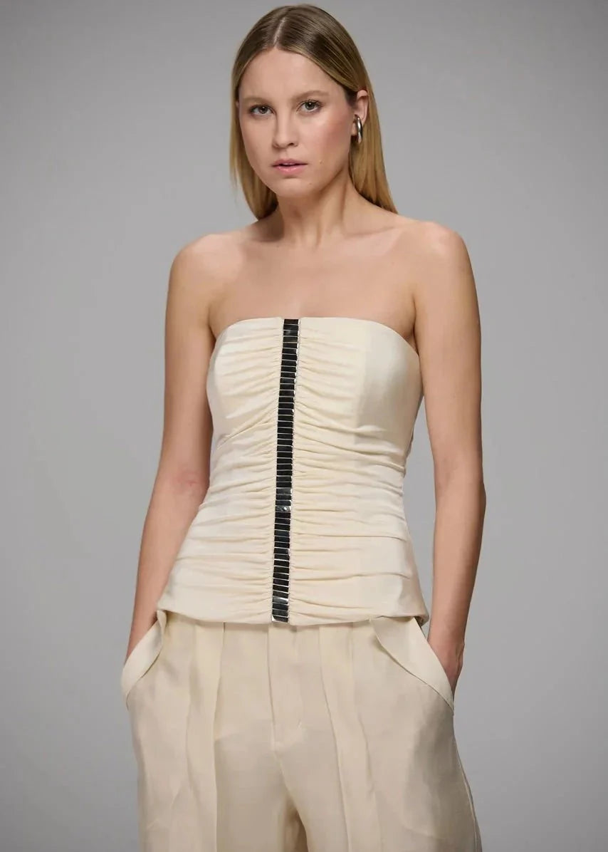 Woman wearing a strapless top and pants with a gray background