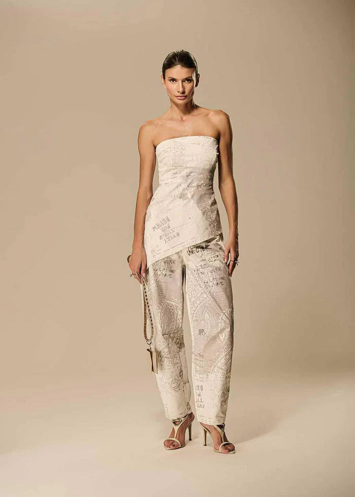 Woman wearing a strapless top and patterned pants on a beige background