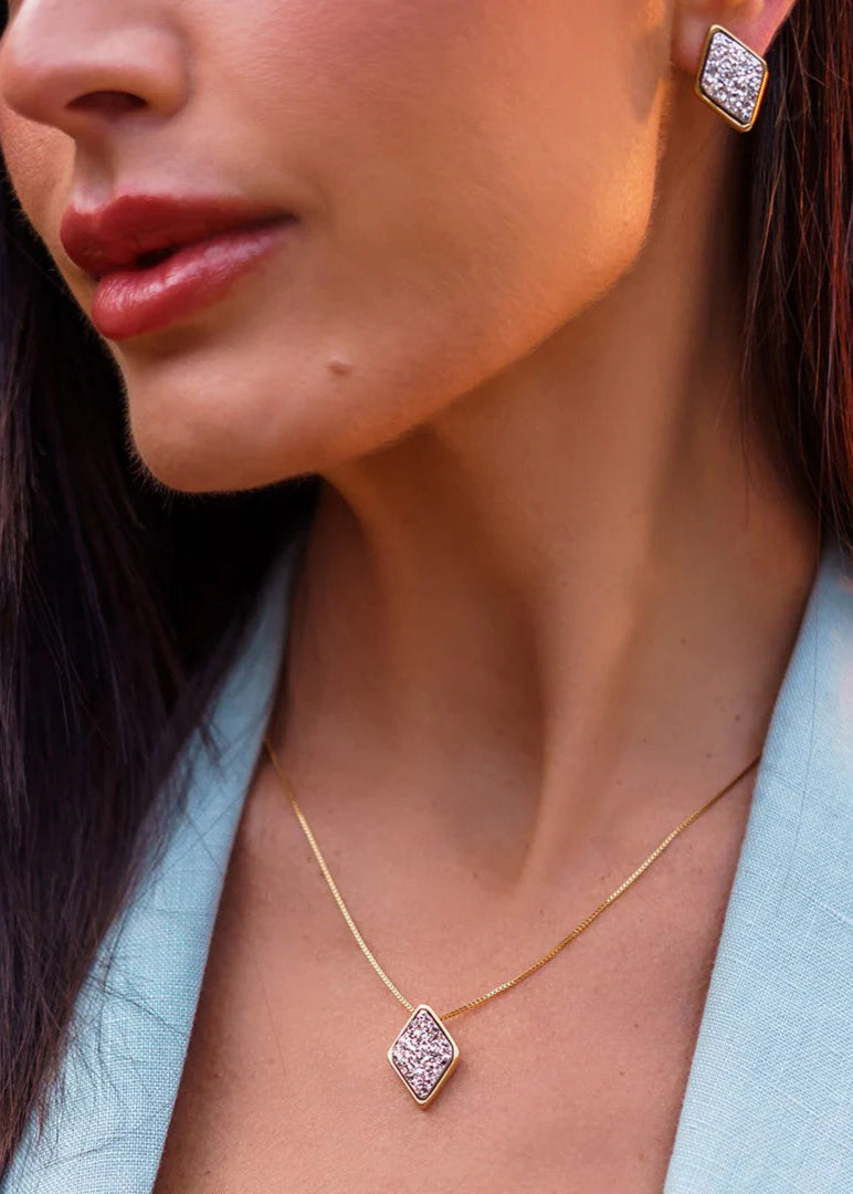 Close-up of a woman wearing a gold necklace and earrings with a blurred background