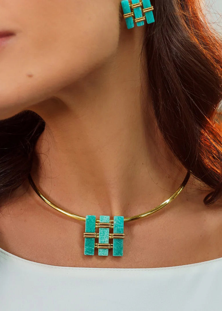 Close-up of a woman wearing a gold and turquoise necklace and earrings.