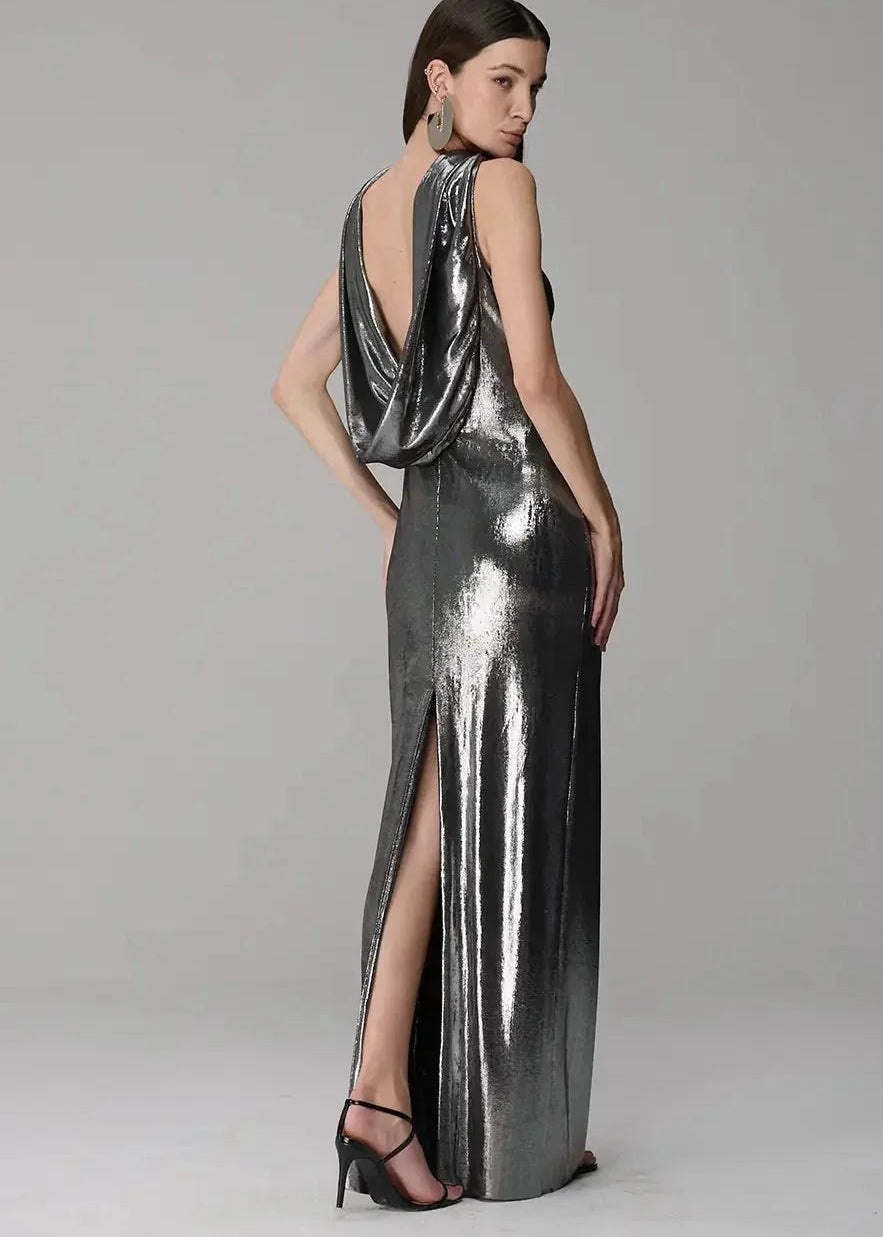 Woman wearing a metallic silver evening gown with a high slit on a gray background