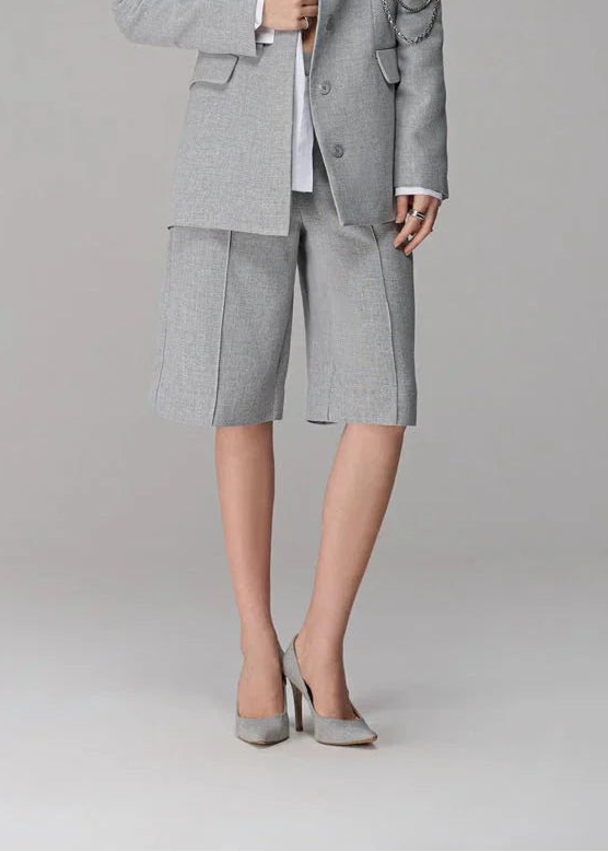 Woman wearing a gray suit with a white shirt on a plain background