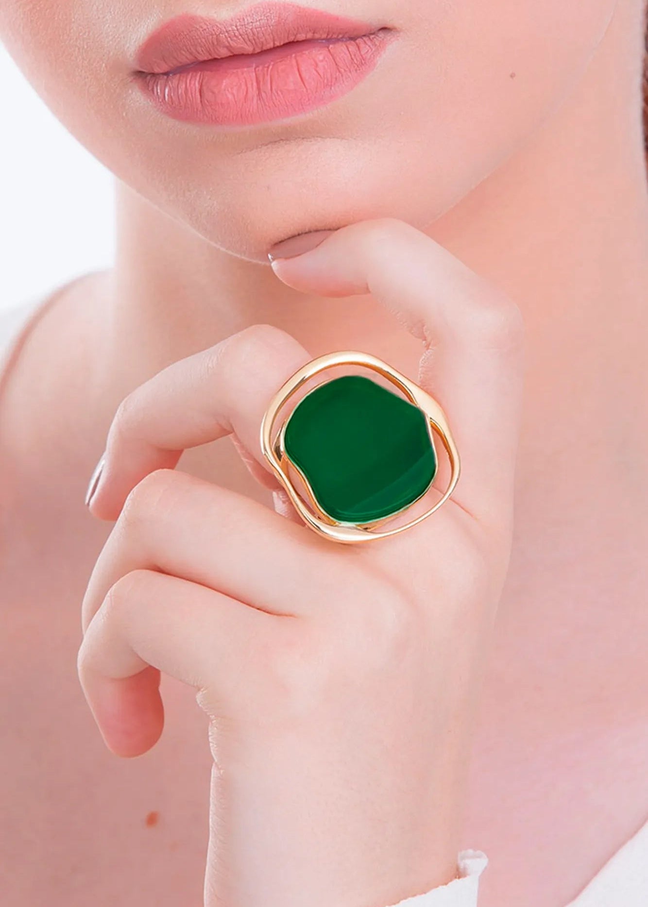 Close-up of a hand wearing a green ring with a gold band.