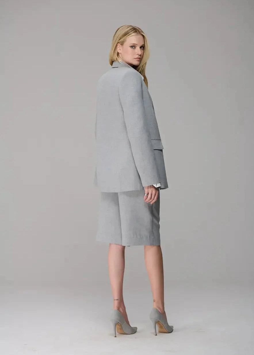 Woman wearing a gray suit standing against a plain background