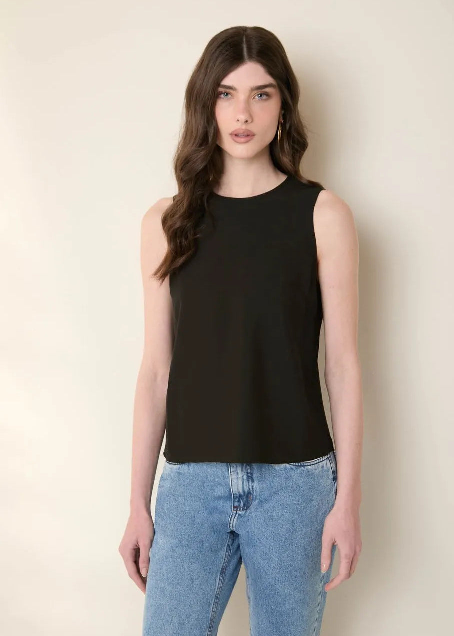 Woman wearing a black sleeveless top and blue jeans against a plain background