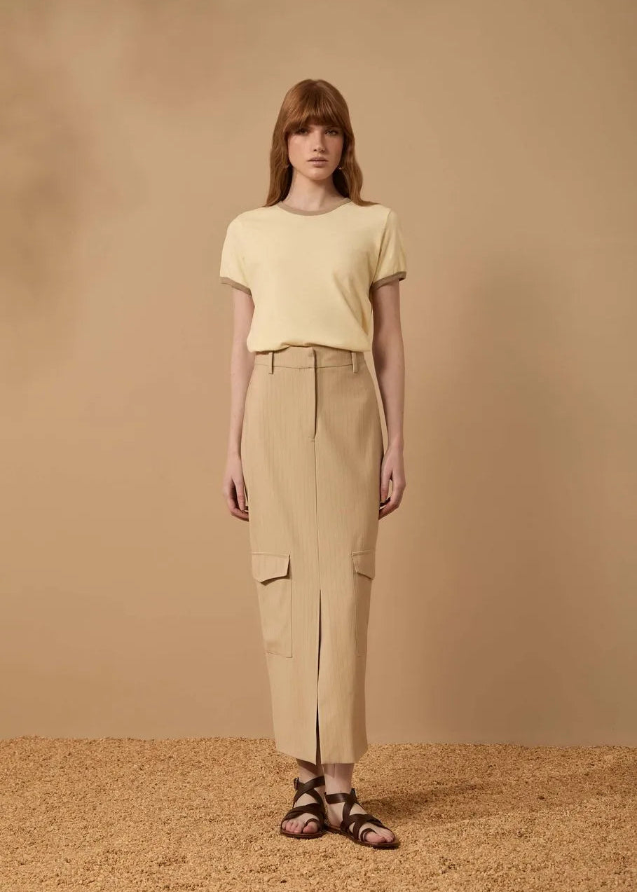 Woman wearing a yellow top and beige pants against a beige background