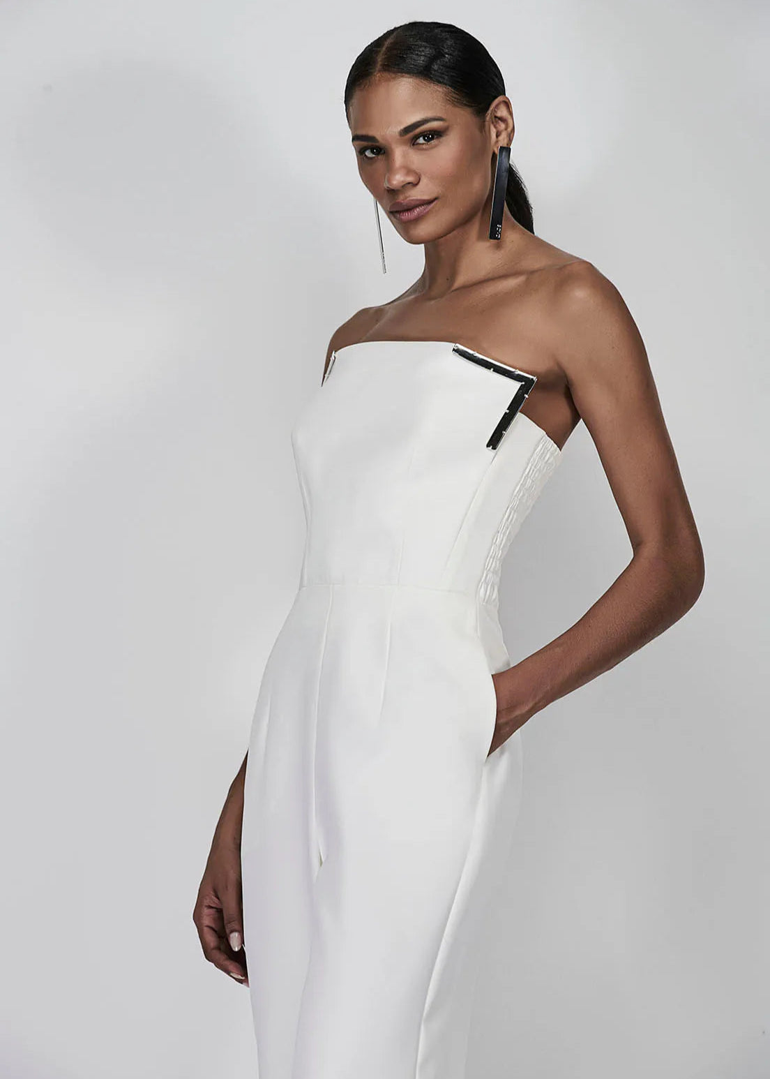 Woman wearing a white one-shoulder dress against a plain background
