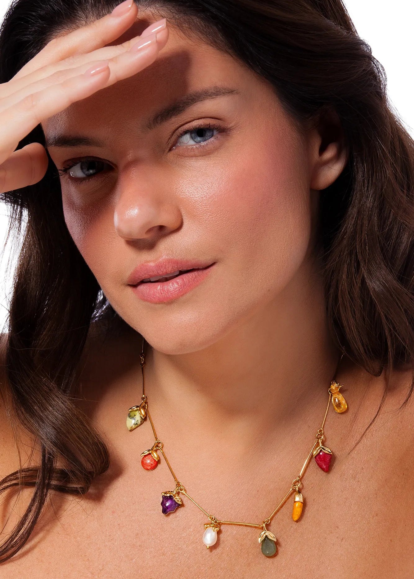 Woman wearing a colorful necklace with various pendants on a white background