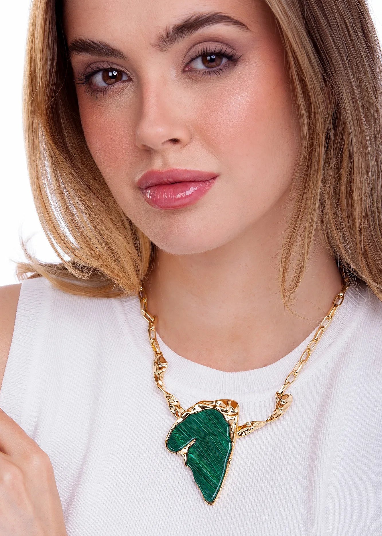 Woman wearing a necklace with a green leaf pendant on a white background